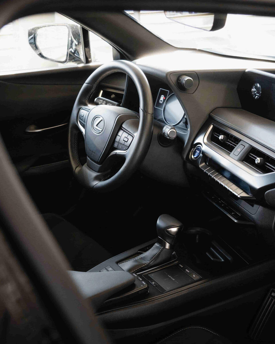 Lexus UX 250h ohjaamo sisältä, ratti ja hallintalaitteet ovat kuvan keskiössä.