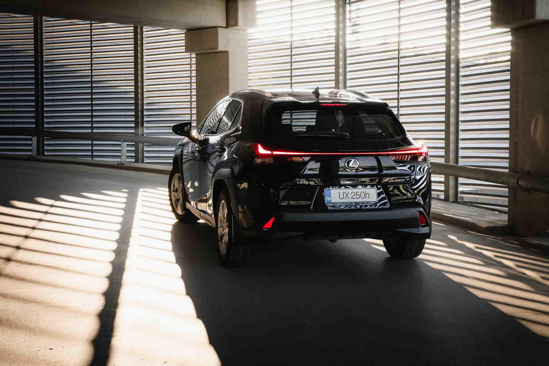 Mainoshenkinen kuva Lexus UX 250h autosta takaviistosta, taustalla parkkihallin seinä.