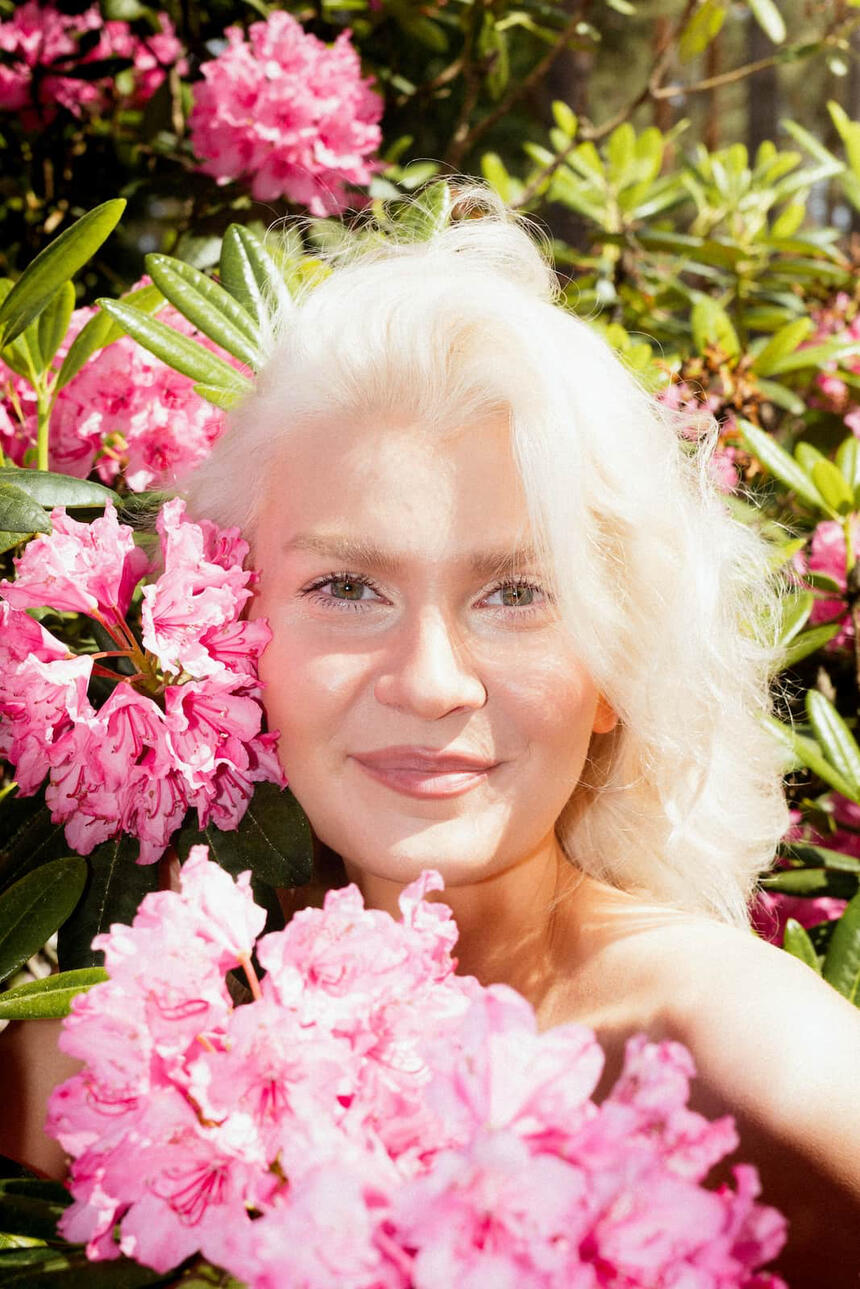 Kuva mallin kasvoista, joita ympäröi alppiruusun kukat.