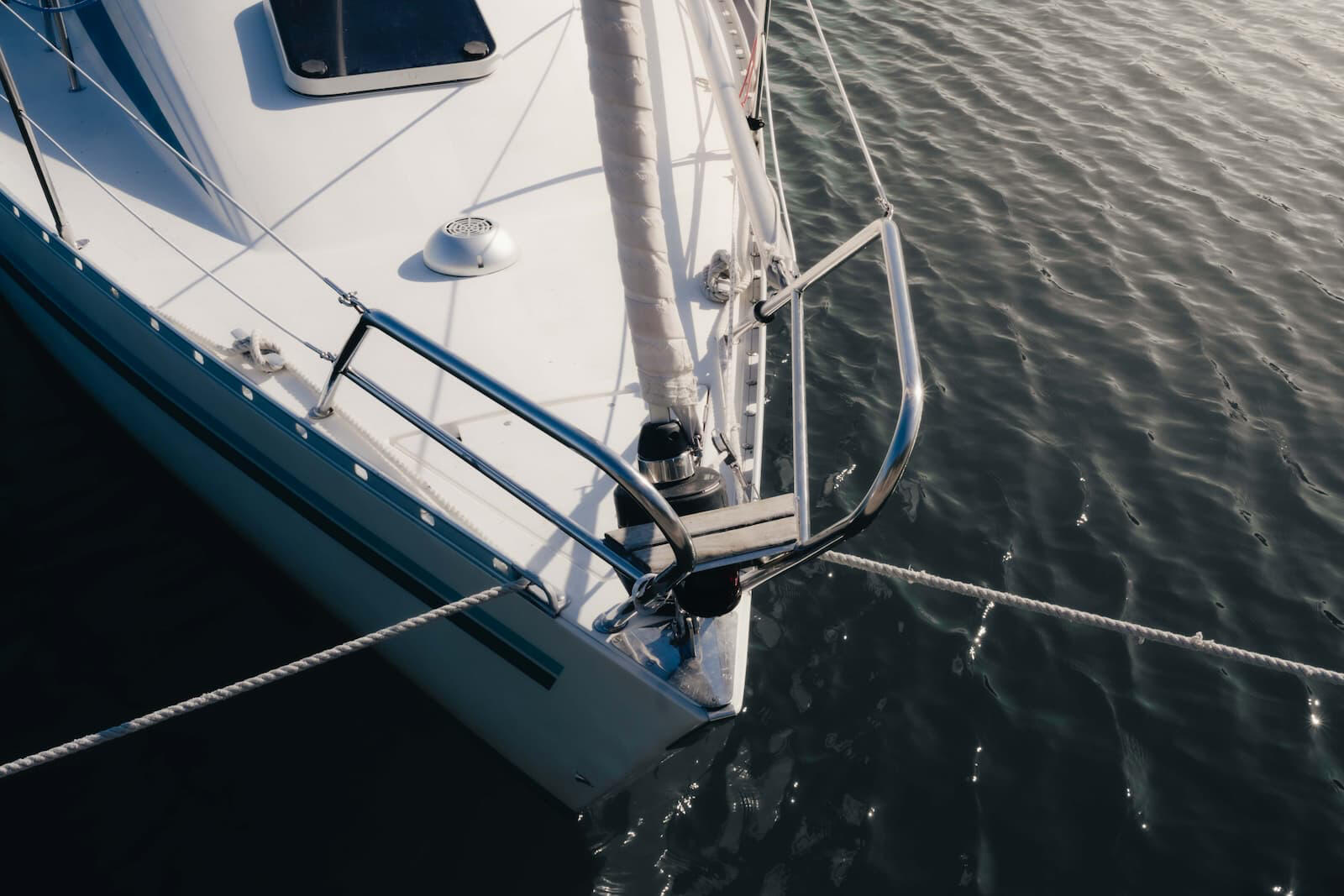 Veneen keula ylhäältä kuvattuna, vedessä kimaltelee auringon valo.