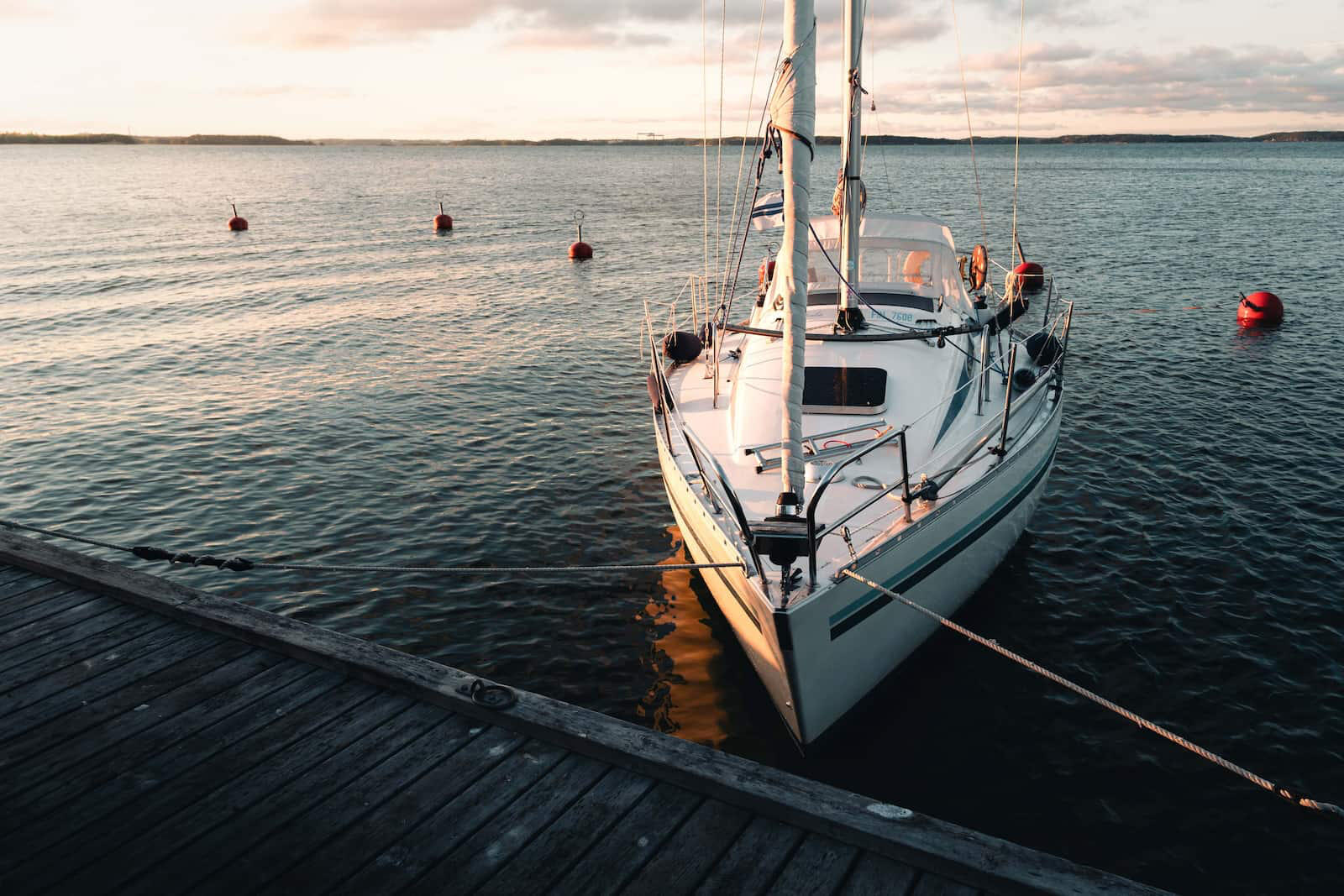 Kuva veneestä joka on kiinnitettu laituriin saaristossa auringonlaskun aikaan.