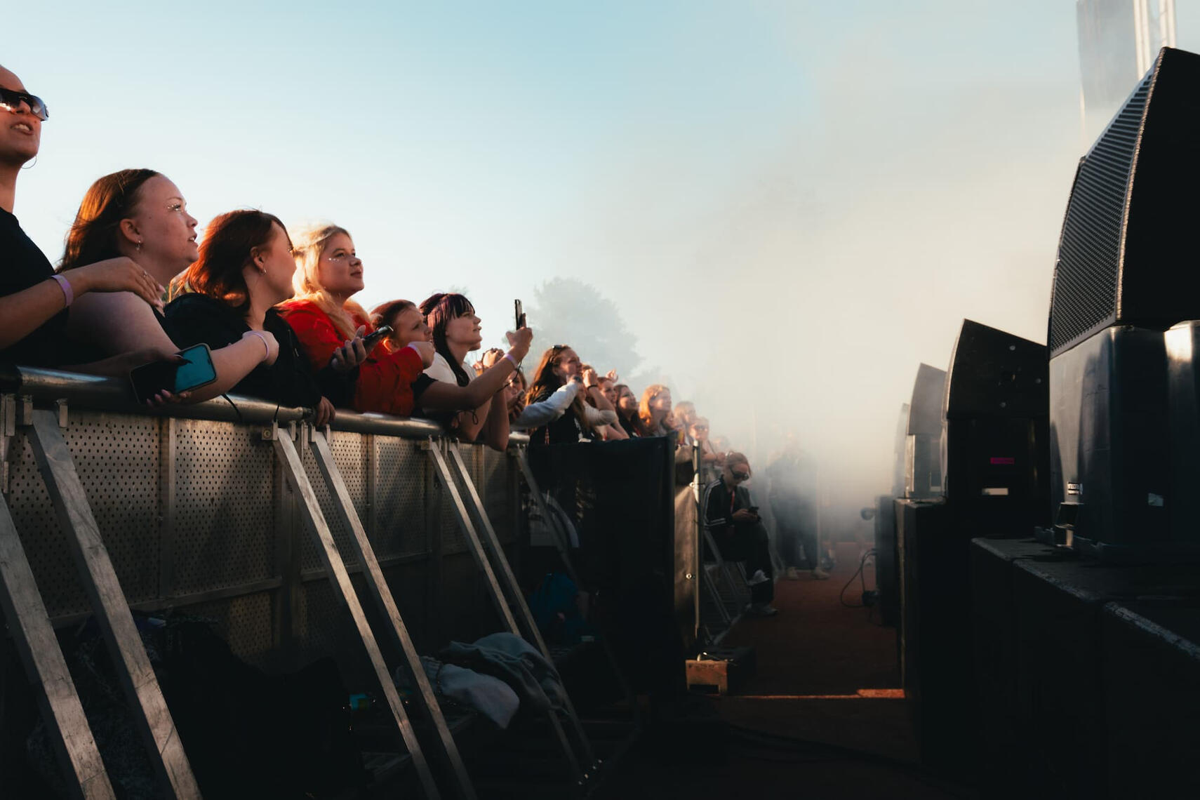 Kuvassa yleisö nojaa aitaan ja hurraa Saarikenttä festivaaleilla.