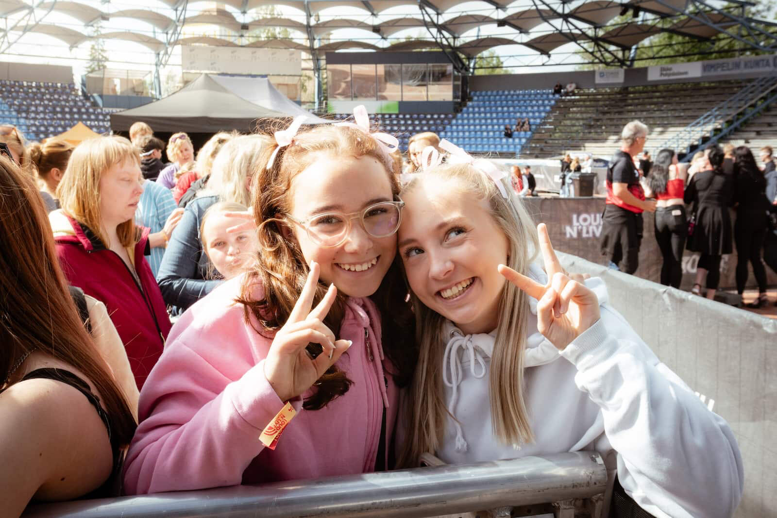 Kaksi nuorta tyttöä hymyilevät kameralle festivaalien yleisössä.