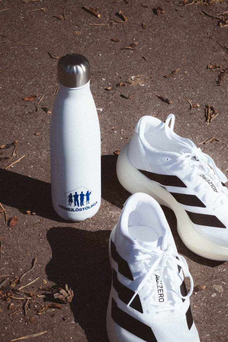 Kuva valkoisesta juomapullosta Adidas juokukenkien vieressä.