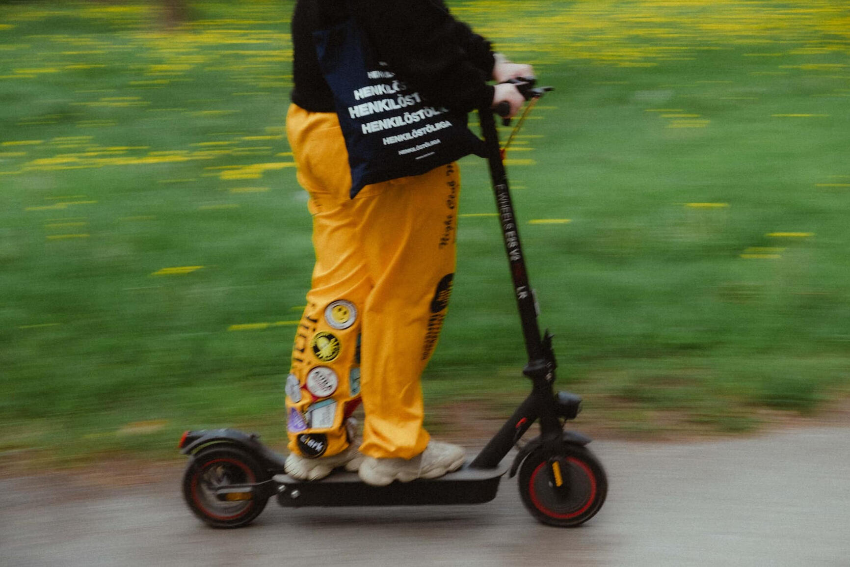 Hitaalla suljinajalla kuvattu kuva jossa henkilö ajaa sähköpotkulautaa keltaiset opiskelijahaalarit jalassa.