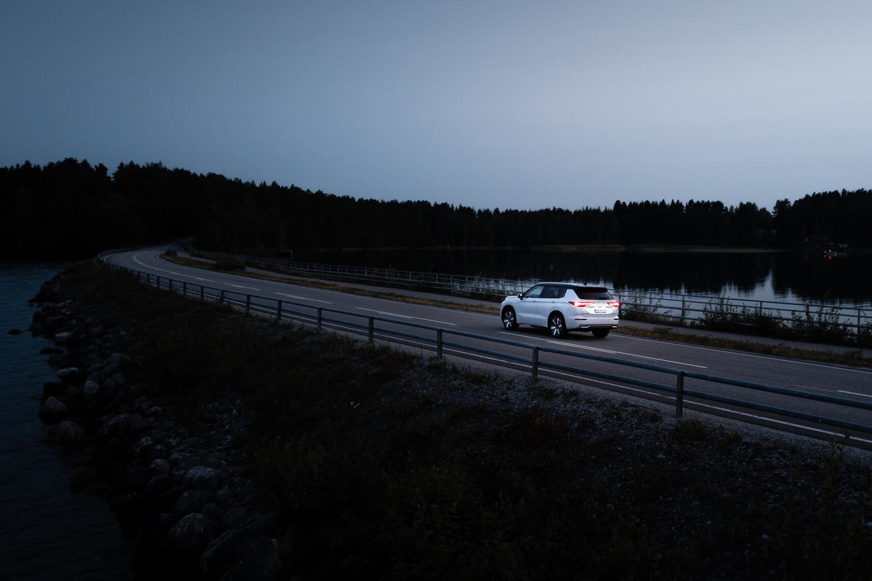 Dronekuva Mitsubishi Outlanderista takaviistosta keskellä suomalaista järvimaisemaa.