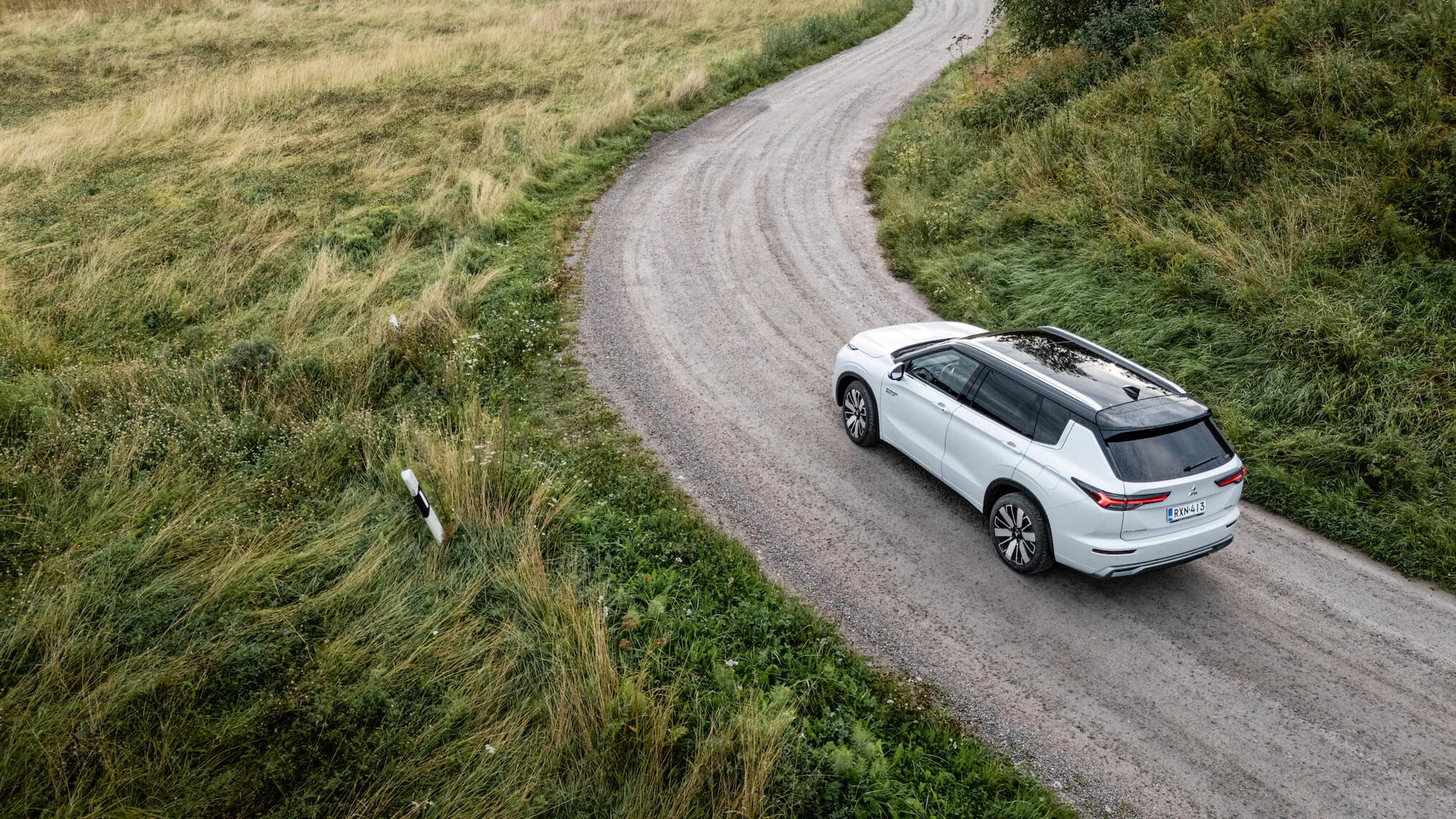 Mitsubishi Outlander yläviistosta kuvattuna mutkaisella hiekkatiellä.