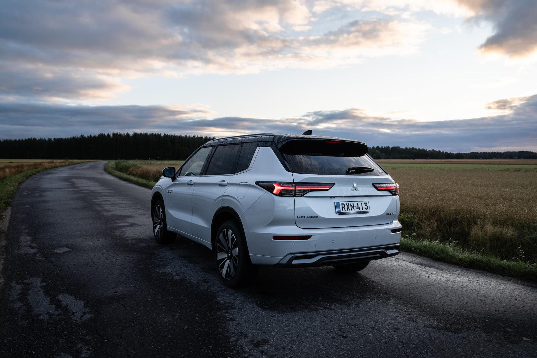 Mitsubishi Outlander kuvattuna takaviistosta keskellä suomalaista peltomaisemaa.