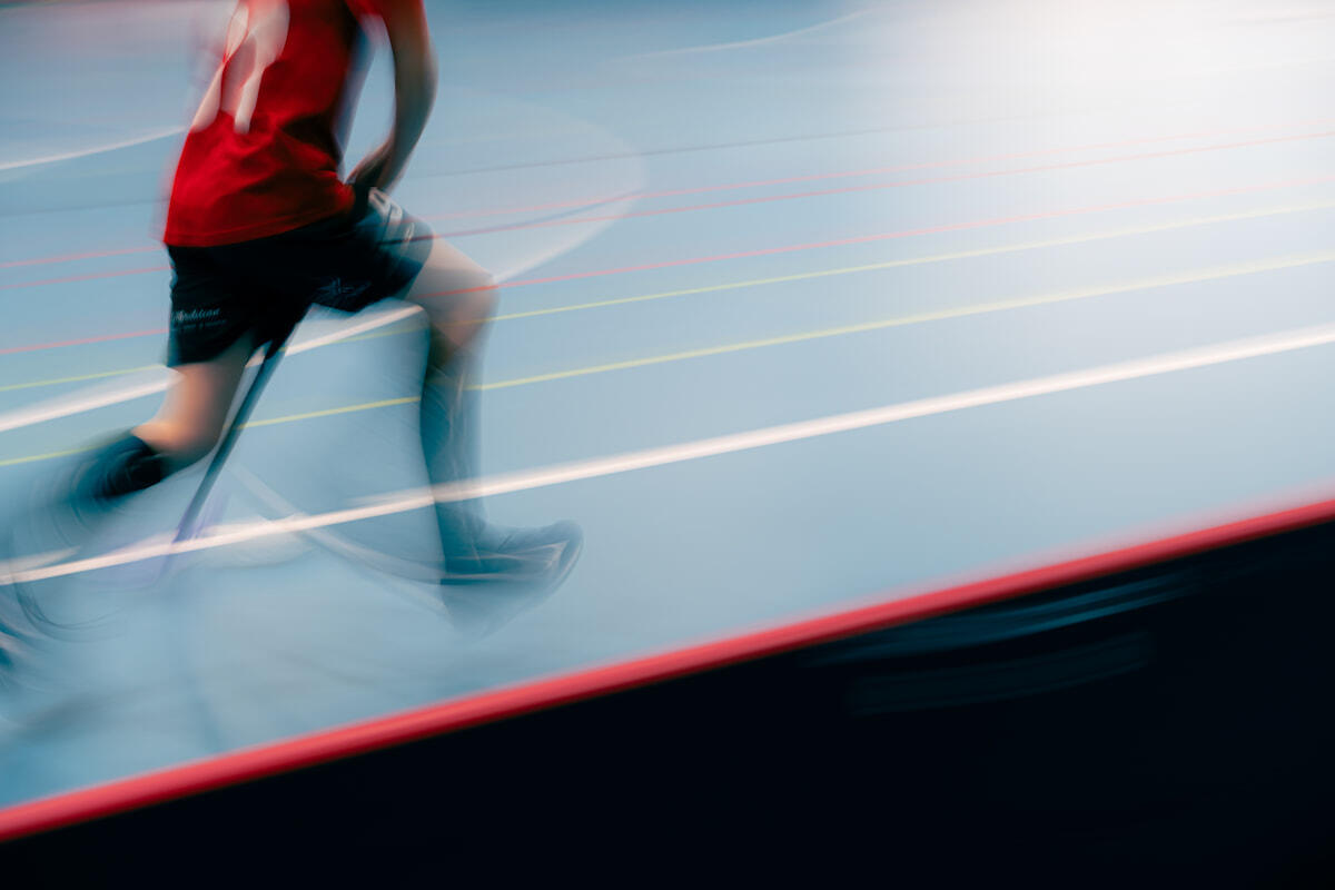 Liikkuva henkilö juoksee salibandykentällä. Kuva on tarkoituksella liike-epäterävä, korostaen vauhdin ja energian tunnetta.