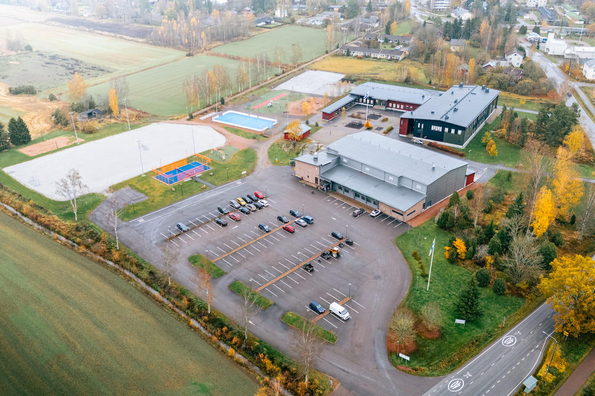 Ilmakuva Vehmaan liikuntahallista ja sen ympäristöstä syksyisessä maisemassa. Kuvassa näkyy pysäköintialue, kentät ja rakennukset ylhäältä käsin.